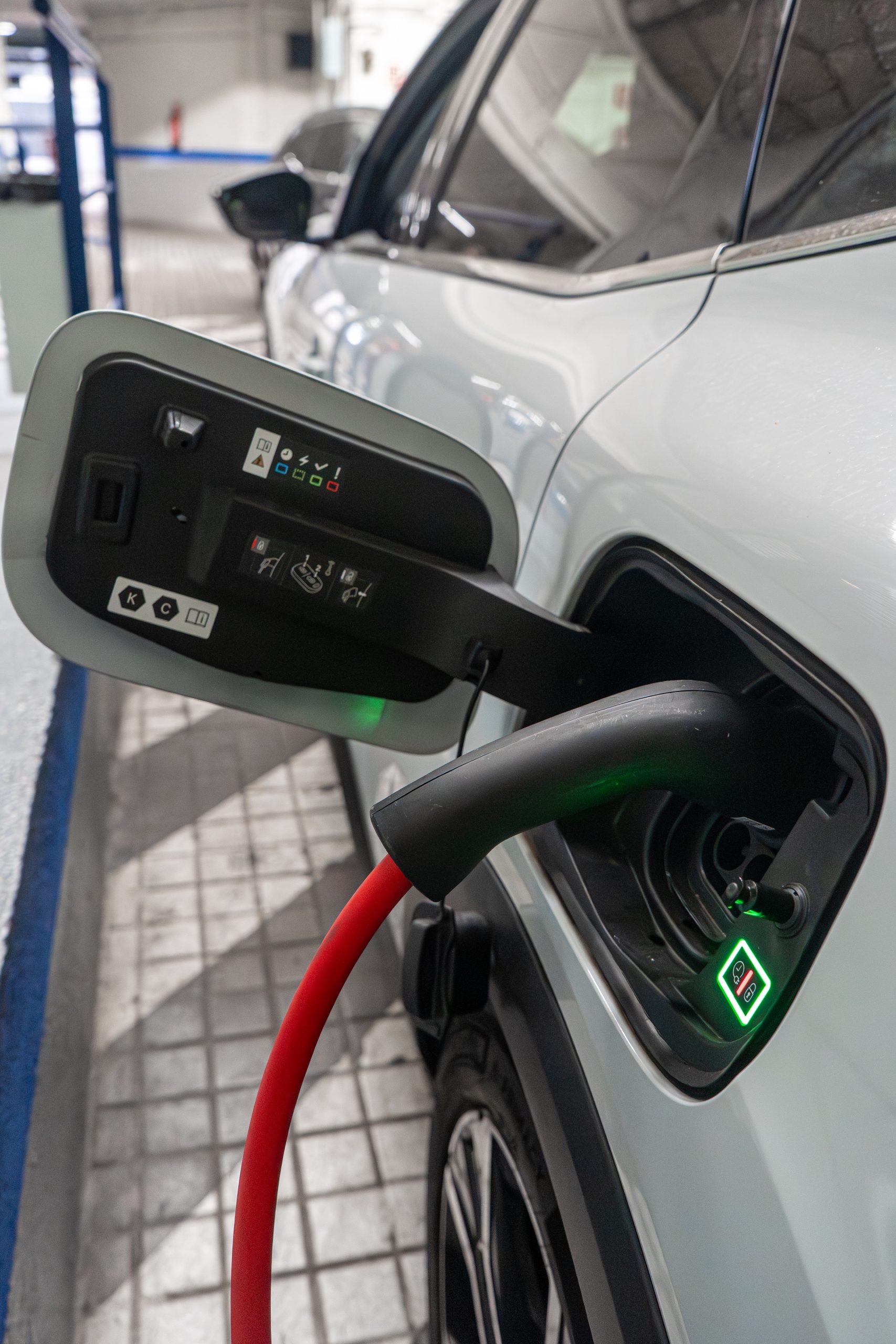 Conector de carga enchufado a un coche eléctrico dentro del parking