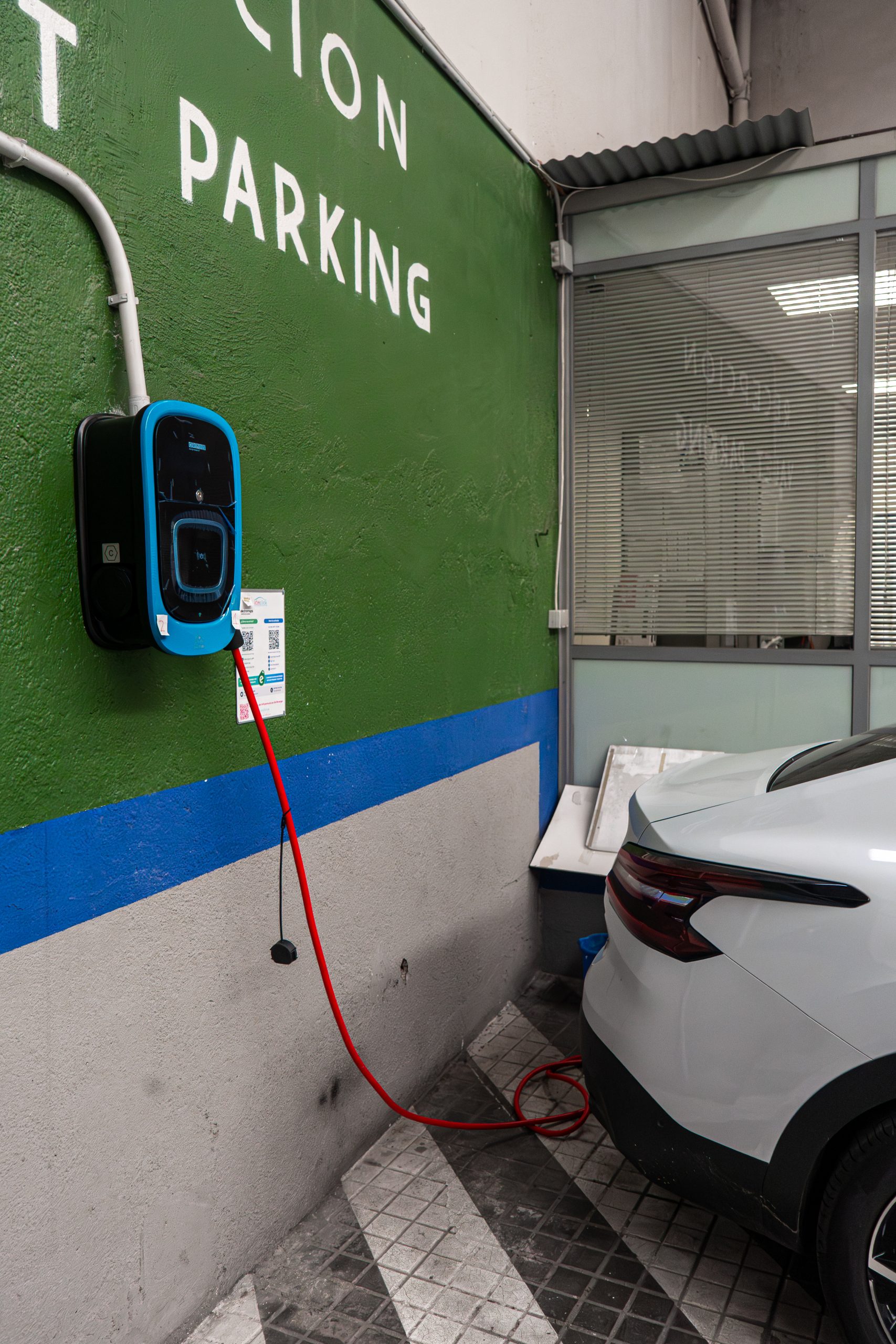 Coche junto a un punto de carga eléctrica en Parking Príncipe de Asturias